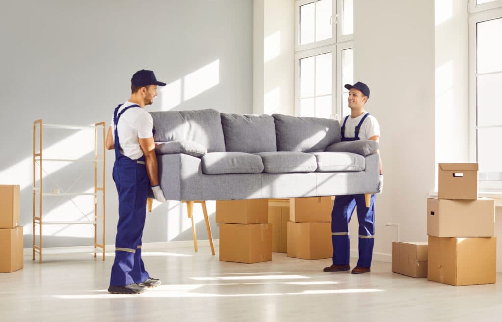 Two workers carrying furniture during a house clearance